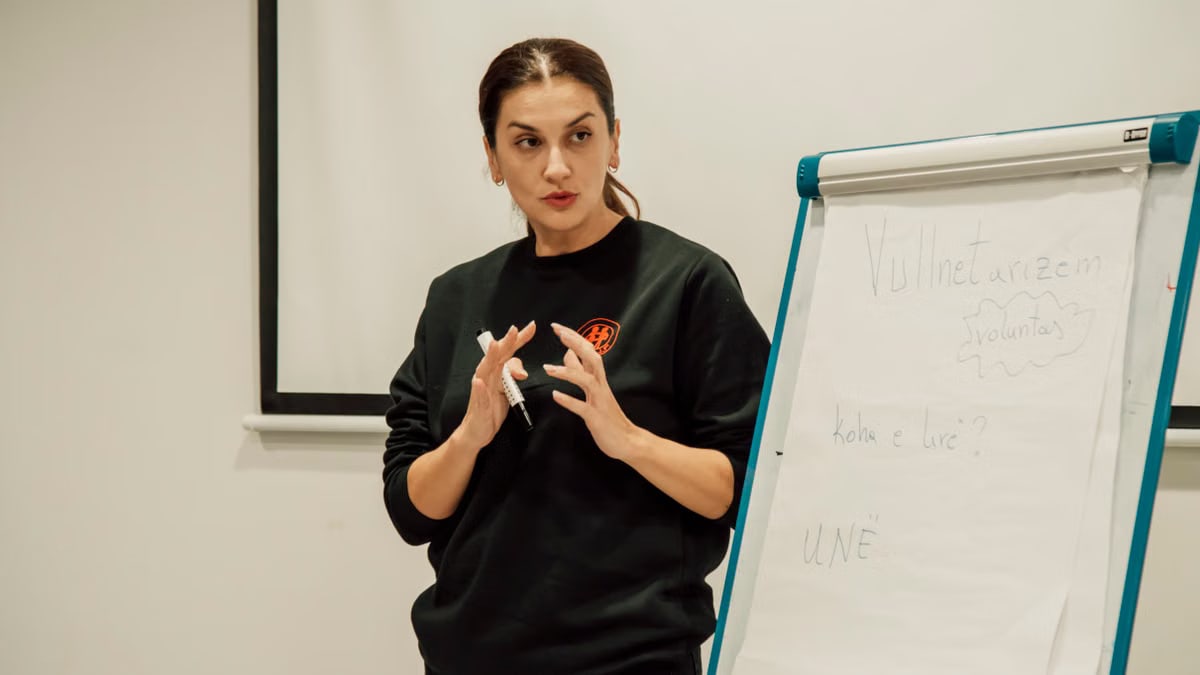 Woman confidently presenting with a flip chart in a classroom setting.